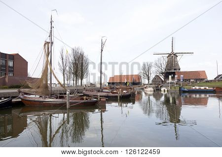 harderwijk, netherlands, 1 april 2016: old harbor in dutch town of harderwijk with windmill De Hoop in the background