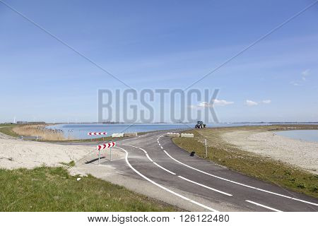 landscape with tractor on dike in flevomeer near zeewolde in dutch province of flevoland