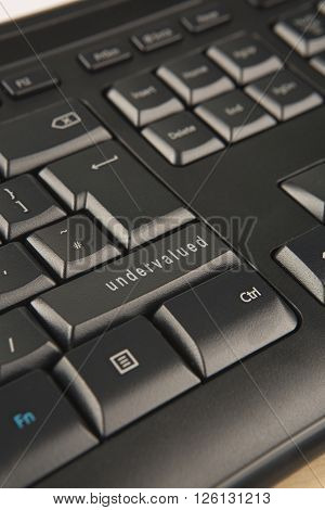 the word undervalued replacing the shift key on a black office keyboard