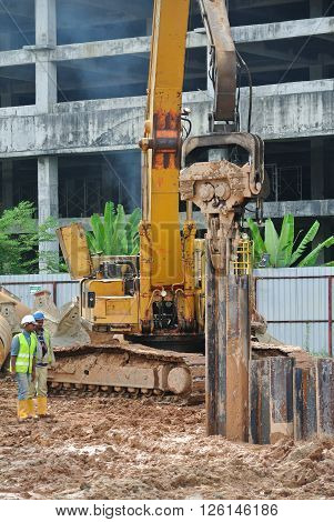 SELANGOR, MALAYSIA -MARCH 25, 2015: Sheet pile cofferdam driven machine at the construction site. The machine drove the sheet pile to the earth using vibrated hydraulic arm. Workers control.