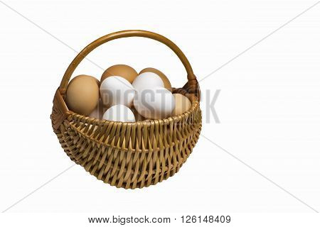 Light brown wicker basket with colorful fresh eggs isolated on a completely white background.