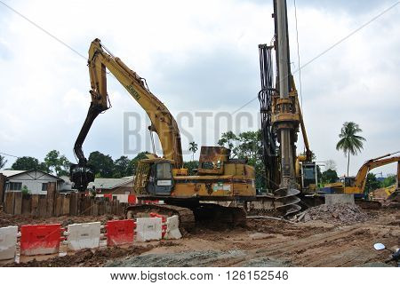 SELANGOR, MALAYSIA -MARCH 25, 2015: Sheet pile cofferdam driven machine at the construction site. The machine drove the sheet pile to the earth using vibrated hydraulic arm. Workers control.