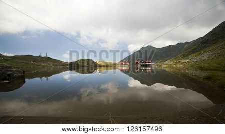 BALEA LAKE, ROMANIA - JULIY 22, 2015: Beautiful view of Balea Lake cottage on Fagaras Mountains, Carpathian, Romania. The image of the chalet is reflected in the lake.