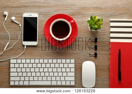 Workplace with mobile phone, peripheral devices and stationery on wooden table