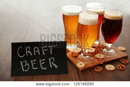 Glasses with different sorts of craft beer and snacks on wooden tray