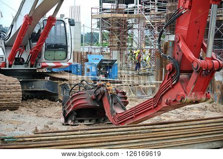 SELANGOR, MALAYSIA -MARCH 25, 2015: Sheet pile cofferdam driven machine at the construction site. The machine drove the sheet pile to the earth using vibrated hydraulic arm. Workers control.