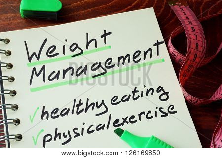 Notepad with sign weight management on a wooden background.