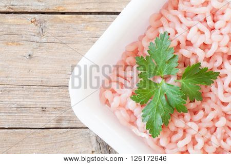 Angle of tray with raw ground turkey meat seasoned with parsley leaf top view shot.