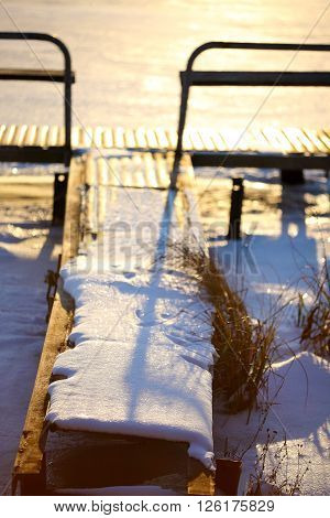 abandoned pier and reeds in winter at sunset. Shallow depth of field