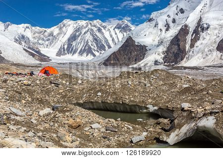 Glacier Crevasse with Melting Water Lake Red Camping Tent Female Hiker and Mountain Panorama with Clean Sky and Shining Sun