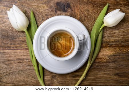 cup of coffee and white tulips on wooden table top view