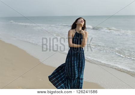 Lady in dark blue dress wandering on the beach