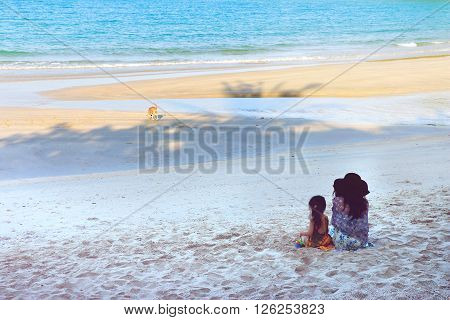 Mother and daughter sitting at the beach on hoiday