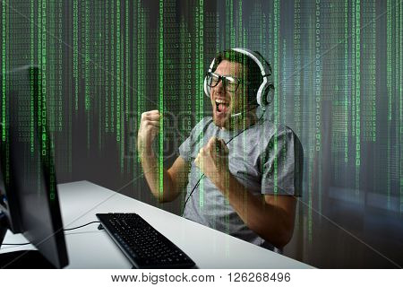 technology, gaming, entertainment, let's play and people concept - happy young man in eyeglasses with headset playing and winning computer game at home and streaming playthrough or walkthrough video