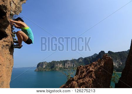 free solo woman rock climber climbing at seaside mountain rock wall