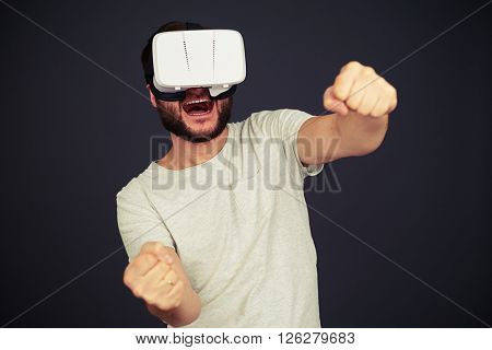 Beard man driving in virtual reality wearing hi-tech VR headset, on black background