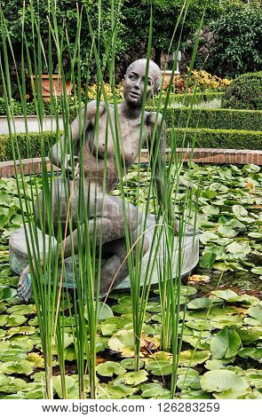 MERAN, TYROL-AUGUST 17, 2015: Woman sculpture in lily pond in gardens of the Trauttmannsdorf Castle. Merano, South Tyrol