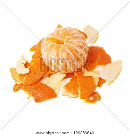 Unpealed cleaned fresh tangerine on a pile of it's peel isolated on white background