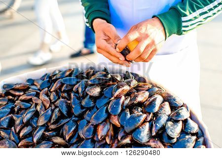 ISTANBUL - MAY 28, 2015: Male hands cleans mussels for quick snackfood in Istanbul. Mussels is very popular street food in Istanbul selling one by one to the tourists