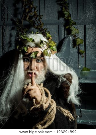 Old man  with rope around hands and vine crown