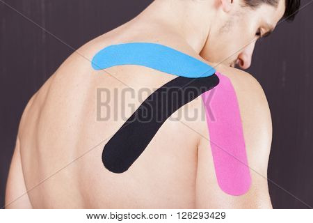Muscular man with kinesiotaping on the shoulder against grunge background
