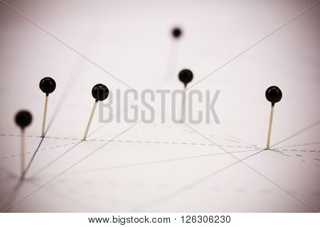 Black Pins In Paper Linked By Lines
