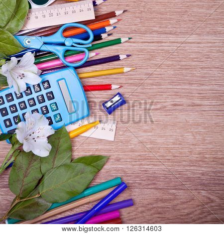 Colored pencils calculator, pencil sharpener, ruler on a wooden board