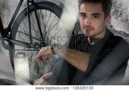 Handsome young man sitting on floor next to black bike