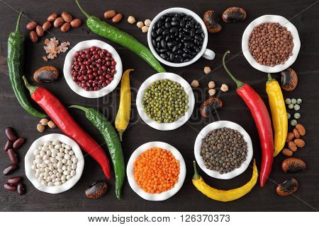 Colorful beans and lentils in ceramic bowls on a dark background.