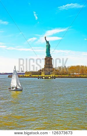 View on a sailing ship and the Statue on Liberty Island USA in Upper New York Bay. Tourists nearby