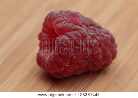 Extremely close-up view of raspberry lying on the wooden kitchen board