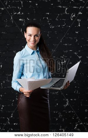 Russian business lady looking straight to the camera on the black brick background for use e.g. in collages, presentation