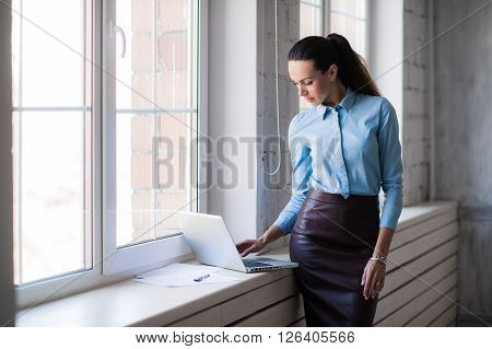 Business lady looking to the laptop near the bright windows