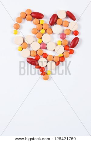 Heart shaped colorful medical pills capsules or supplements for therapy on white background concept of treatment and health care copy space for text