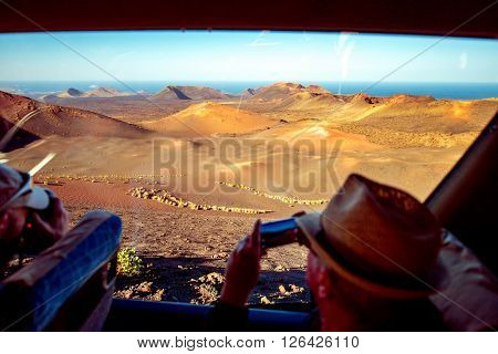 TIMANFAYA PARK, LANZAROTE ISLAND, SPAIN - SIRCA JANUARY 2016: Man makes pictures of volcanic landscape during bus excursion in Timanfaya park. Timanfaya park is entirely made up of volcanic soil