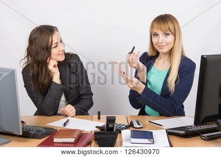 Office Employee At His Desk Looking At His Colleague, Who Is Holding Lipstick And Mirror In Hand