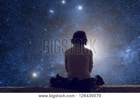 Silhouette of a lonely woman while watching the stars and Milky Way at night.