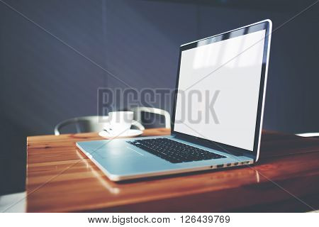 Portable net-book and cup of hot cappuccino lying on wooden table in contemporary coffee shop interior freelance work via internet open laptop computer and mug of cafe in modern office space