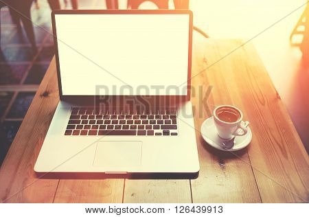 Portable net-book with blank copy screen screen for your information content or text message laptop computer lying on wooden table in cafe bar interiorfreelance work via internet during coffee break