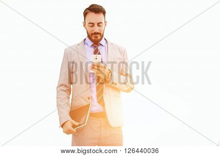 Man skilled financier dressed in luxury suit is holding portable touch pad and reading information in web site via cell telephone while is standing near copy space for your advertising text message