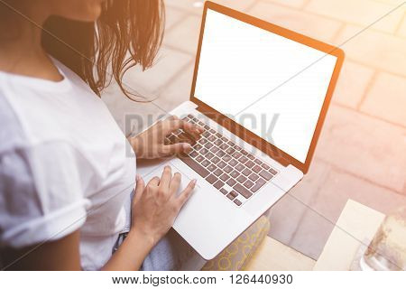 Back view of female student is typing text on laptop keyboard during class break in cafe. Woman freelancer is working on net-book with mock up blank copy space screen for your text message or concept