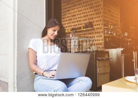Creative woman designer is working on laptop computer during breakfast in modern coffee shop. Female freelancer connecting to cafe wireless for remote work via net-book. Student girl learning on-line
