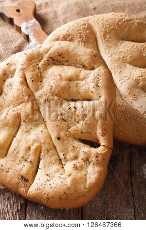 French Bread Fugasse With Sesame Seeds And Herbs Macro On The Table. Vertical