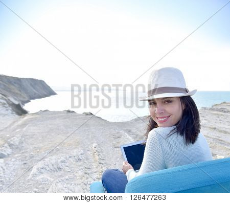 Woman using laptop by the sea, sit in armchair