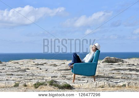 Woman in armchair relaxing on a cliff by the sea