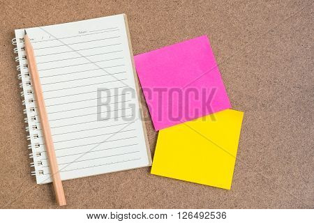 Top view of open spiral notebook empty line paper with brown pencil and colorful sticky notes - notebook paper on brown background