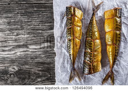 Smoked fish Mackerel or Scomber on a white parchment paper on an old wooden table studio lights top view