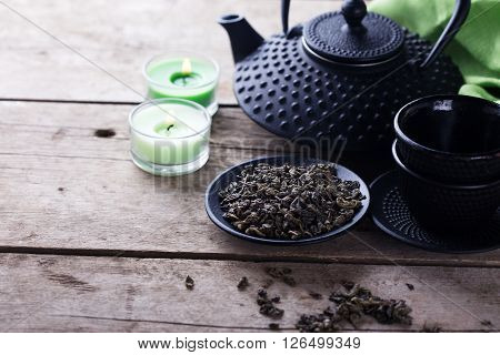 Green tea in bowl and traditional asian tea set on aged wooden background. Selective focus is on tea. Place for text.