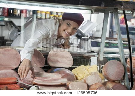 Saleswoman Arranging Products In Display Cabinet At Grocery Stor
