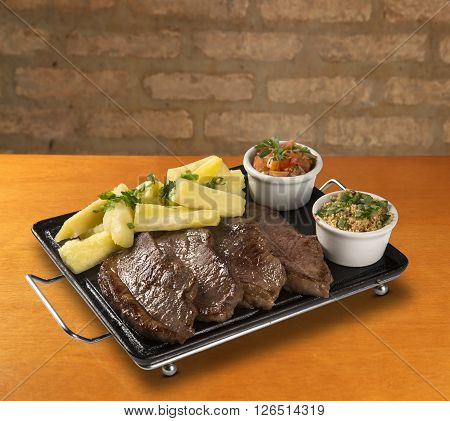 picanha portion and manioc fries. wood background.
